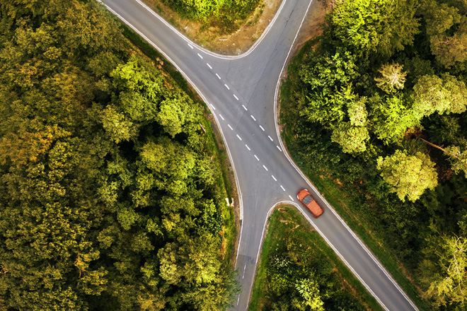 ariel image of car driving on road in middle of forest