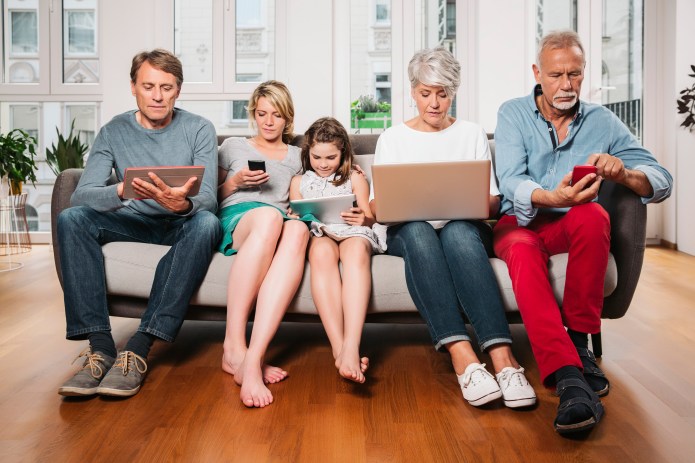 Family sits together and looks at their mobile devices