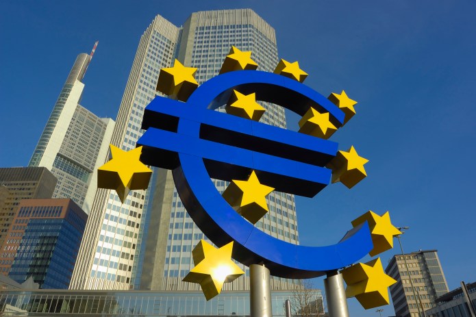 Image of the European central bank in Frankfurt and the blue and yellow sign of the euro in front of it