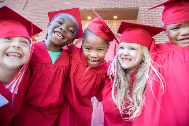 Adorable diverse group of preschool students smile for photo at graduation event