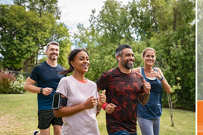 four diverse people jog happily in a park together