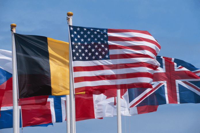 Flags of various countries blowing in the wind with the Stars and Stripes, the flag of the United States, at the front and most prominent.